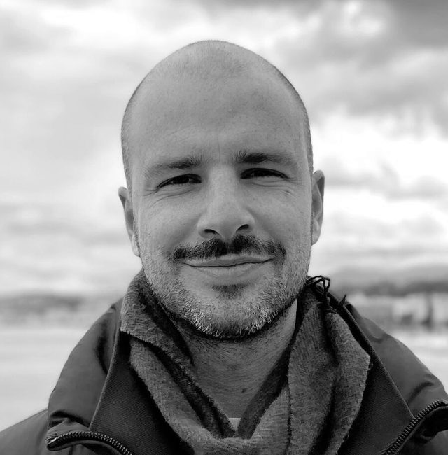 Retrato de Diego Lajst, diretor da Stemma, sorrindo, de casaco azul e cachecol, com o mar ao fundo